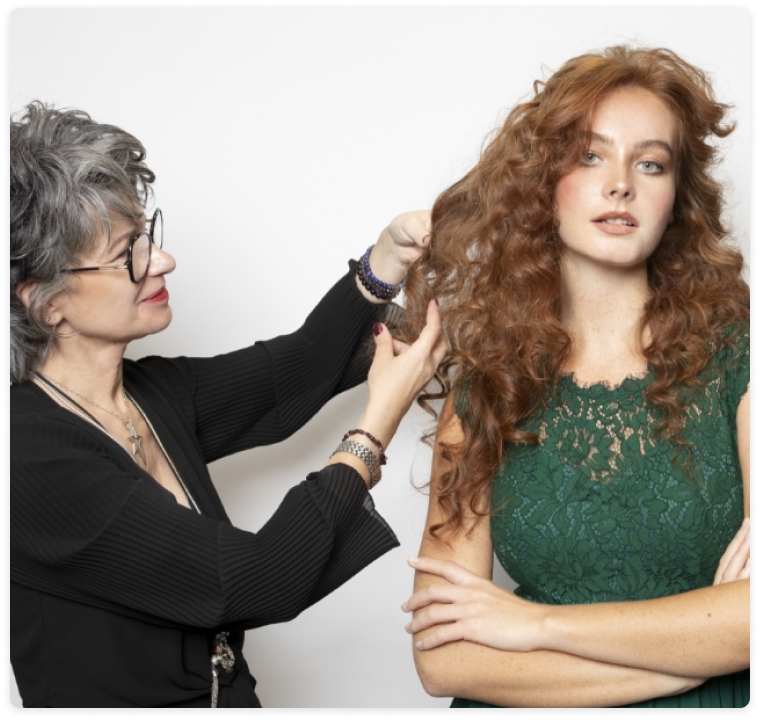 Coiffeuse en train de s'occuper d'une femme avec des cheveux roux ondulés