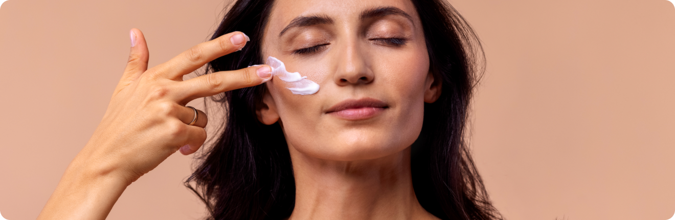 Femme fermant les yeux et appliquant une crème sur le visage avec sa main