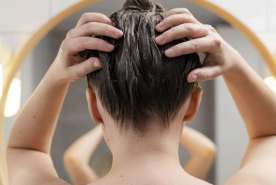 Femme appliquant un soin pour les cheveux devant un miroir